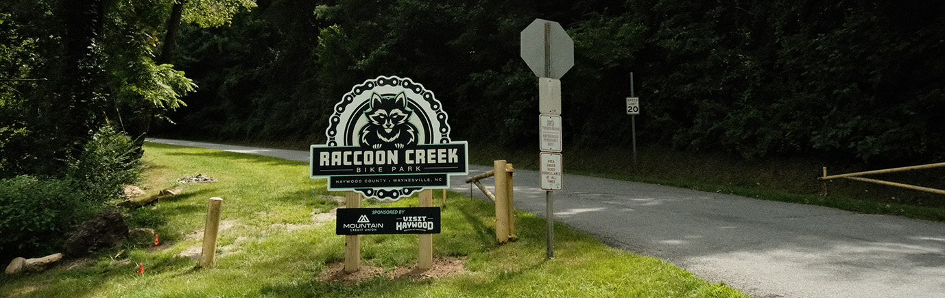 Raccoon creek bike park in Haywood county - showing sign with logo of raccoon within a circular bicycle chain