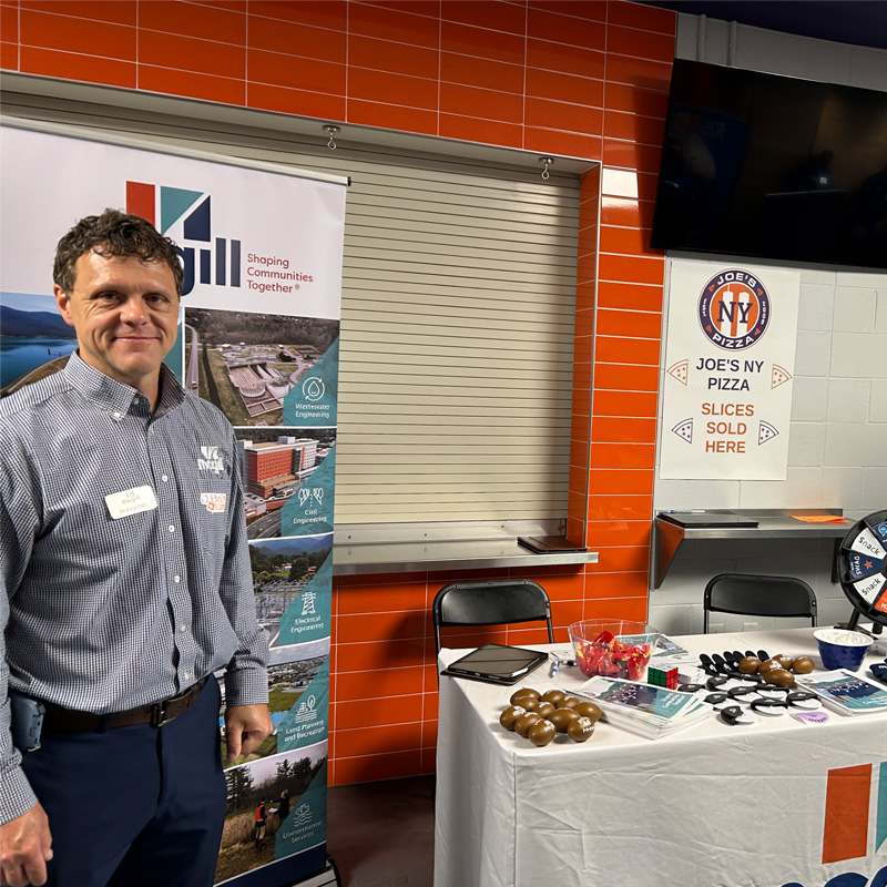 Ben Cathey standing in front a table with swag items on it at the Clemson Career fair