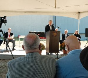 A Decade in the Making: The West Lumberton Floodgate 6 Governor Josh Stein speaking to crowd at West Lumberton Floodgate dedication ceremony. People seated under tent. Camera at left.